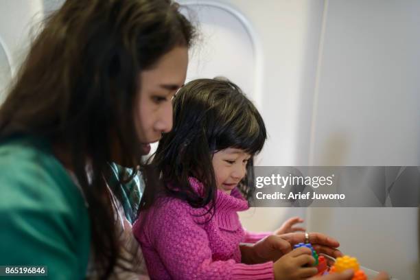 girls playing with mom in airplane - bilingue photos et images de collection