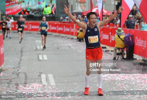Guoxiang Wang celebrates at the finish line during the Scotiabank Toronto Waterfront Marathon in Toronto. October 22, 2017.