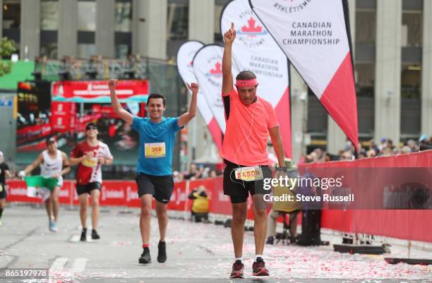 Victor Casasola of Mexico raises his arm at the finish line during the Scotiabank Toronto Waterfront Marathon in Toronto. October 22, 2017.