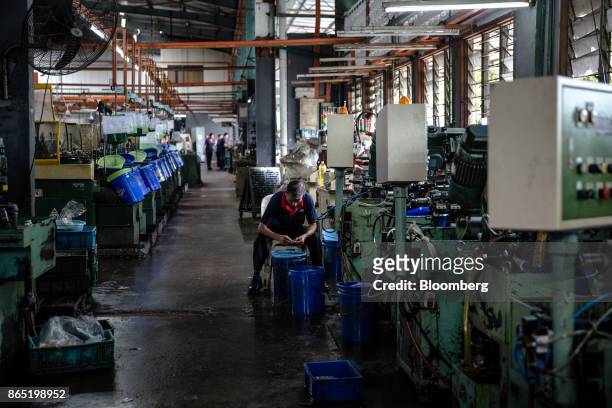 An employee cleans self-clinching fasteners on the production line at a Techfast Holdings Bhd. Manufacturing facility in Shah Alam, Selangor,...