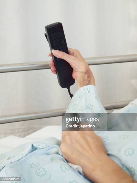 sick woman in a hospital bed adjusting bed height with remote control - ストレプトミセス ストックフォトと画像