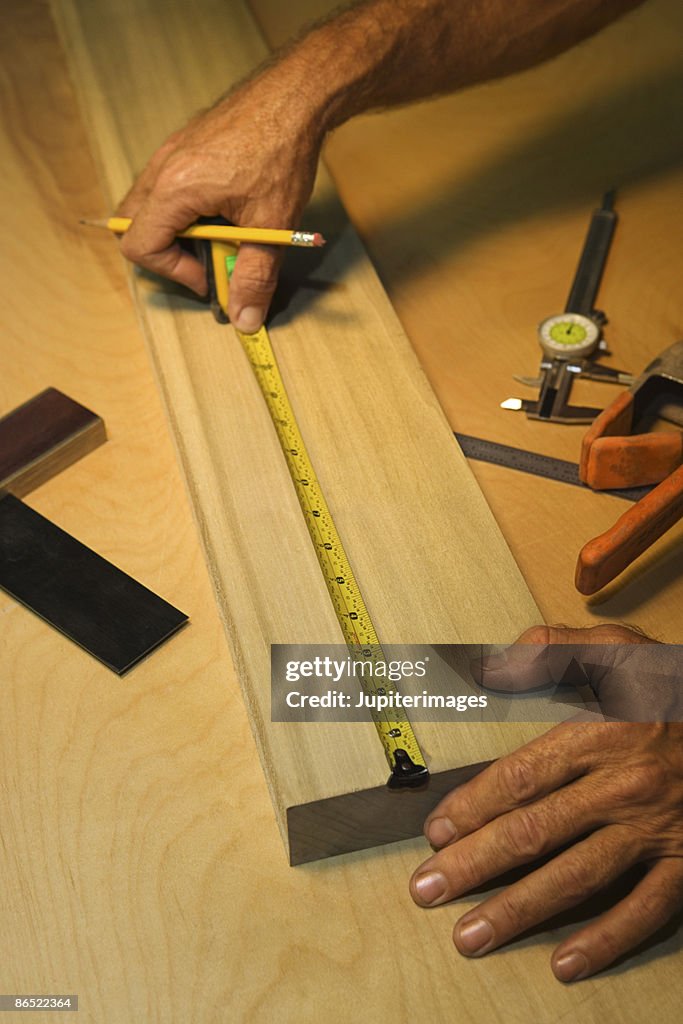 Hands measuring wood