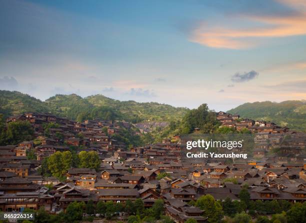 aerial view of mountains behind the traditional wooden houses of xijiang miao ethnic minority village in guizhou, china - hmong stockfoto's en -beelden