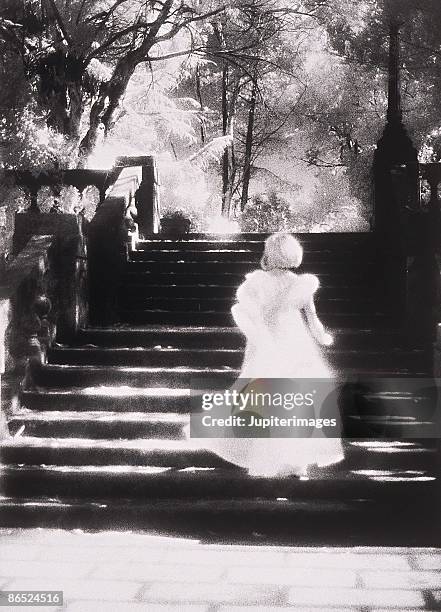 woman wearing gown running up stairs - angel white dress stock pictures, royalty-free photos & images