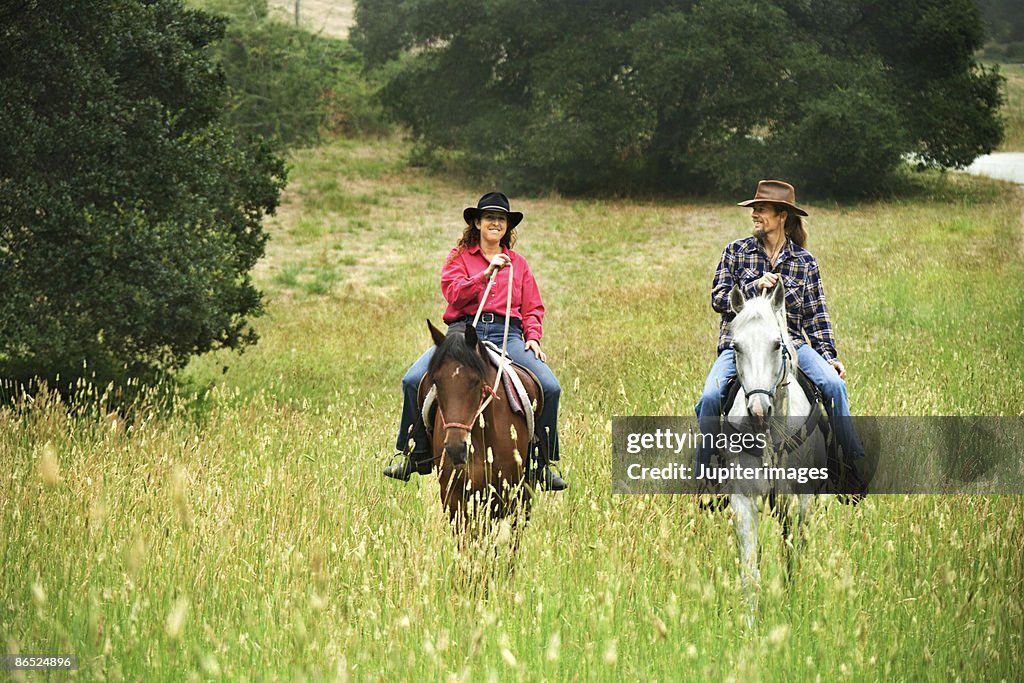 Couple riding horses in field