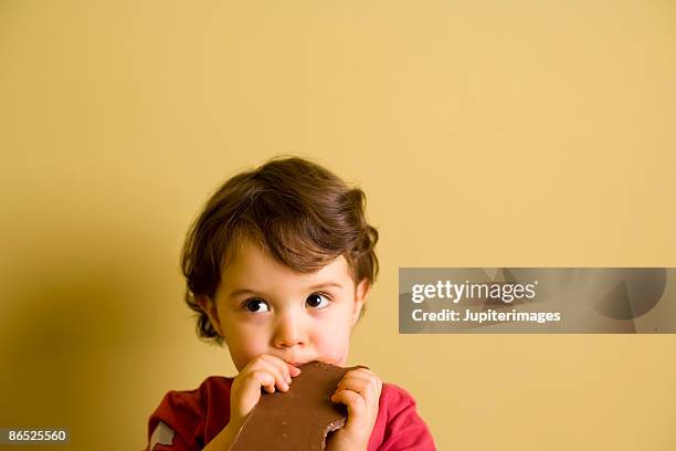 boy eating chocolate bar - biting into chocolate stock-fotos und bilder