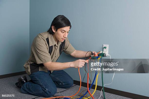 man plugging computer wires into outlet - electrical overload stockfoto's en -beelden