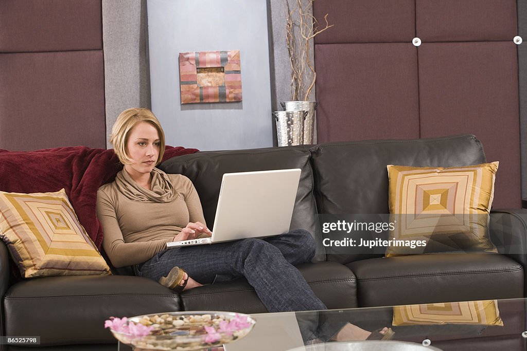 Woman sitting on couch with laptop computer