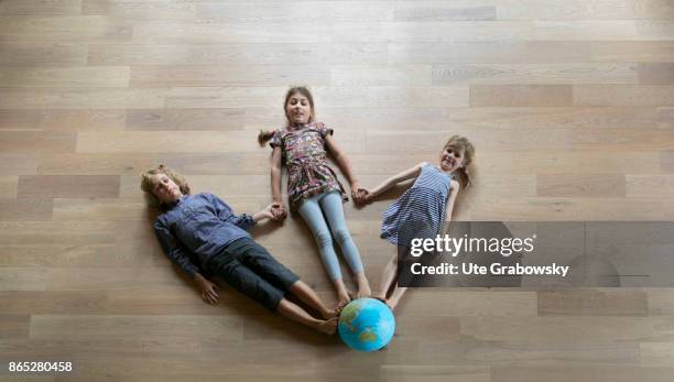 Sankt Augustin, Germany Two girls and a boy are standing on a globe holding their hands on August 08, 2017 in Sankt Augustin, Germany.