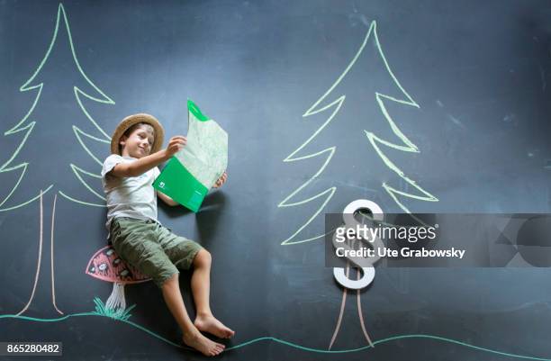 Sankt Augustin, Germany Boy with hiking map and paragraph sign in an illustrated forest in front of a blackboard on August 08, 2017 in Sankt...