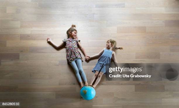 Sankt Augustin, Germany Two girls standing hand-in-hand on a globe and look at each other on August 08, 2017 in Sankt Augustin, Germany.