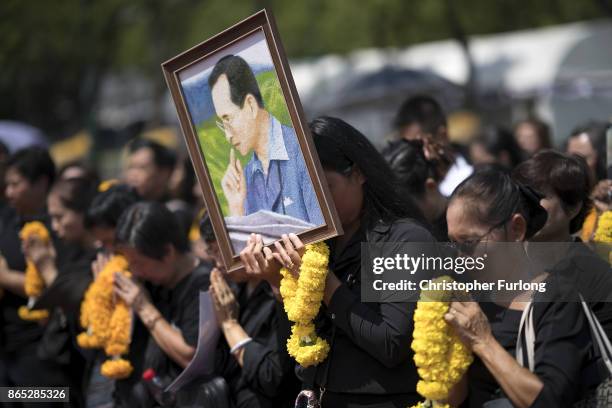 People gather outside the Royal Palace to pay their respects to Thailand's late King Bhumibol Adulyadej, as the city prepares for his cremation on...