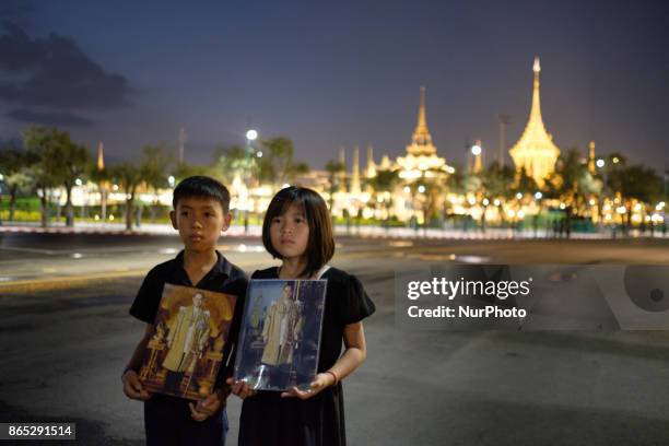 Mourners pose with pictures of the late Thai King Bhumiphol Adulyadej in front of the Royal Crematorium in Bangkok on October 22 2017