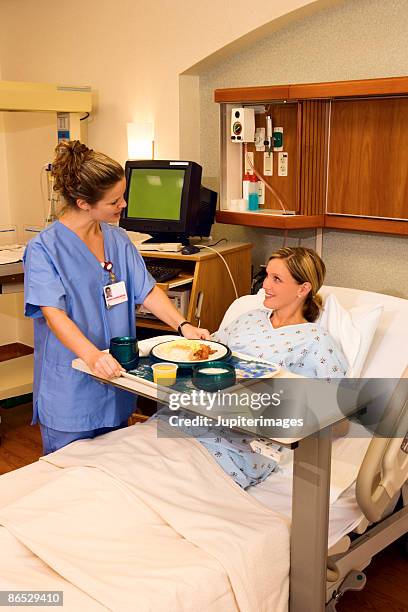 nurse serving woman a meal in the hospital - hospital food stock pictures, royalty-free photos & images