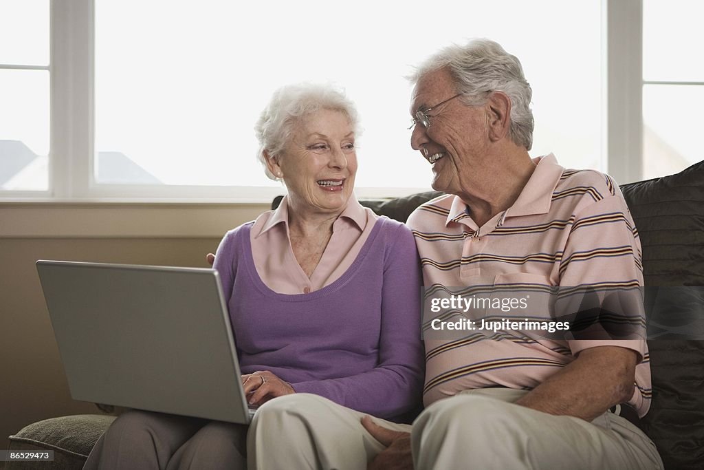 Smiling couple using laptop