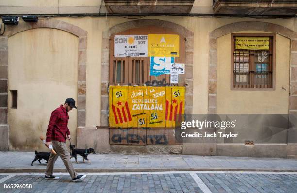 Man walks his dogs past Catalan pro-independence graffiti on a doorway on October 23, 2017 in Barcelona, Spain. The Spanish government is to take...