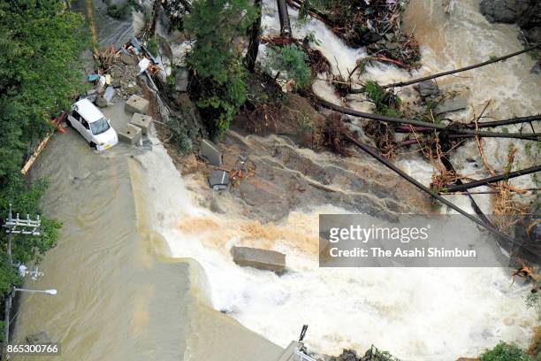 In this aerial image, a car stranded on a road inundated with river water, where an elderly woman was found dead after Typhoon Lan hit past Japan on...