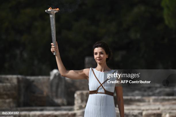 Actress Katerina Lechou acting the high priestess passes the Olympic flame at the Temple of Hera on October 23, 2017 during a dressed rehearsal of...