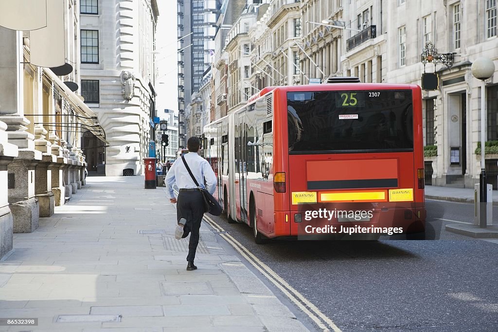 Businessman running after bus in London, England