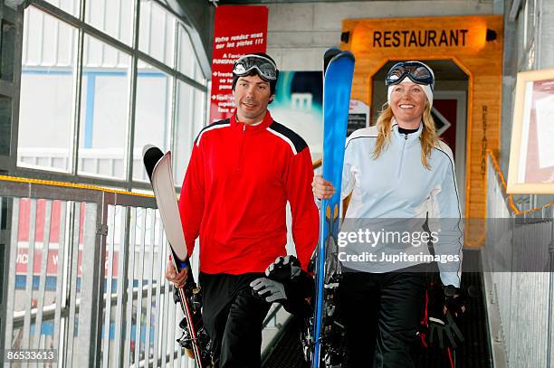 couple carrying ski equipment - woman blond looking left window photos et images de collection