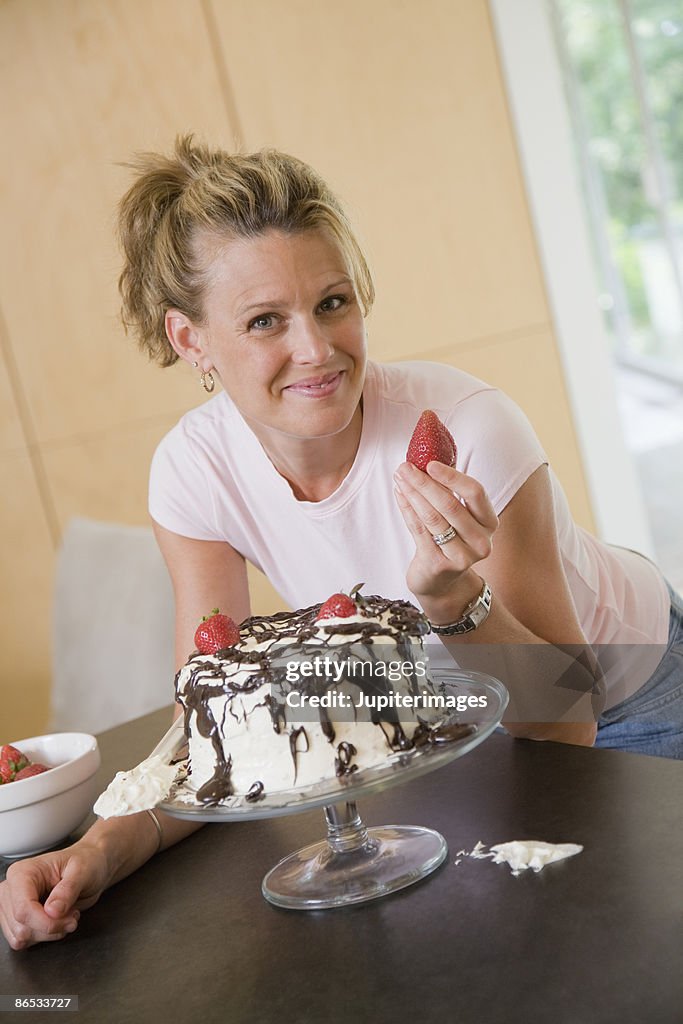 Woman posing with strawberry and cake