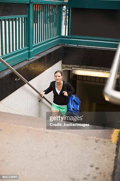 woman with gym bag walking out of subway station - carrying sports bag foto e immagini stock
