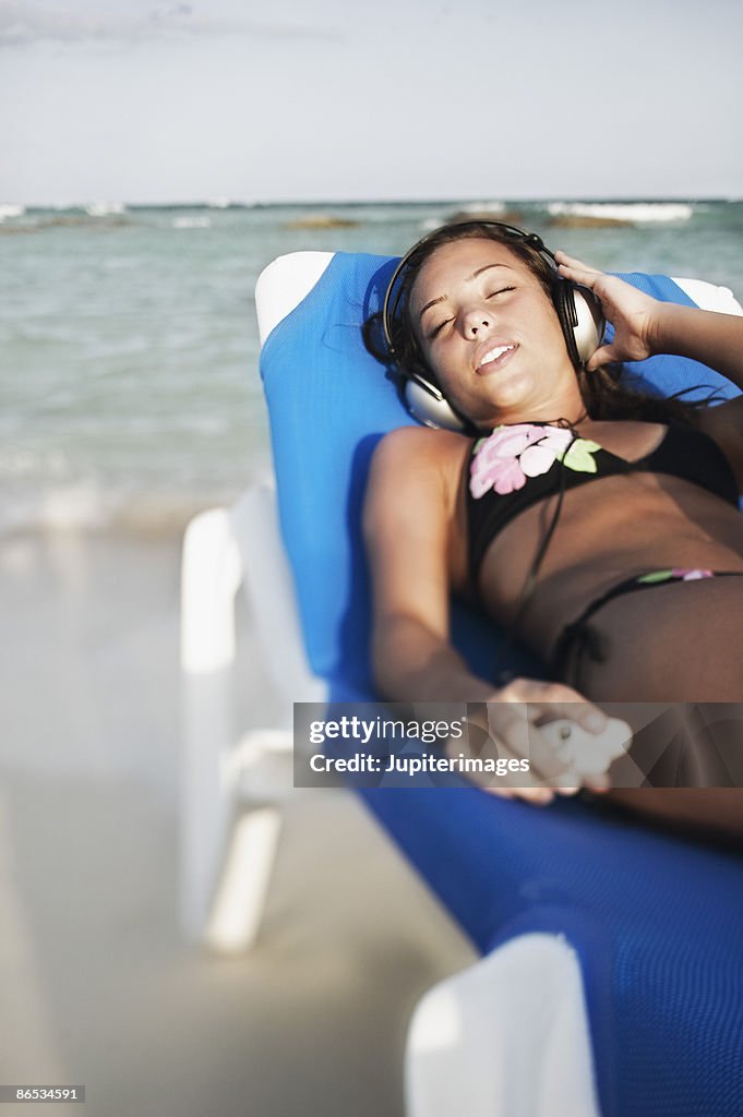 Teenage girl in lounge chair listening to music