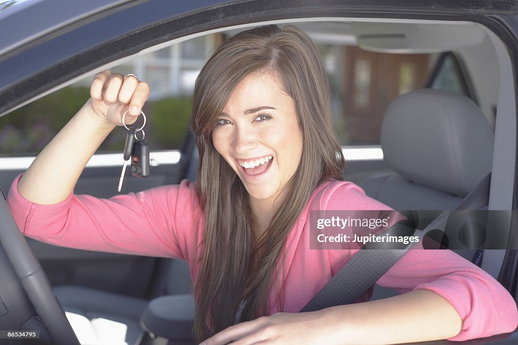 Smiling teenage girl holding keys inside car