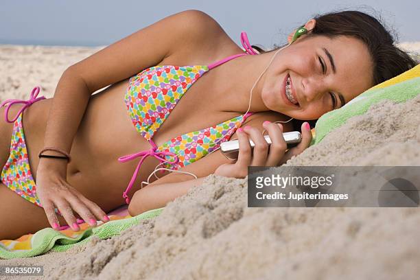 girl relaxing on beach with media player - girls sunbathing stock-fotos und bilder