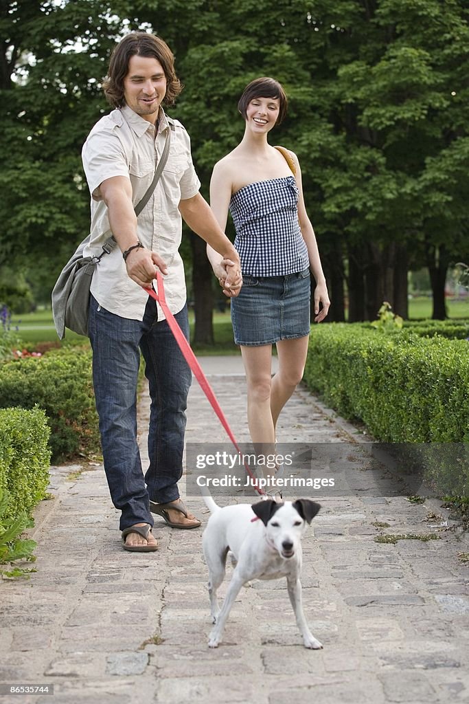 Couple walking dog in park