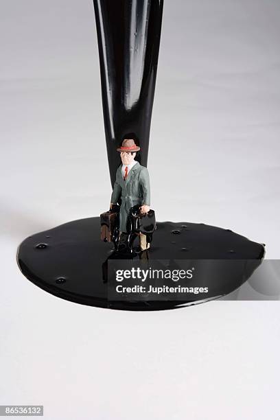 figurine of businessman in pouring oil - slimy businessman stock pictures, royalty-free photos & images