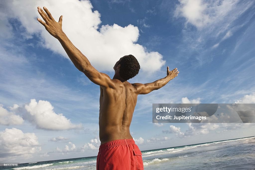 Man on beach with arms outstretched