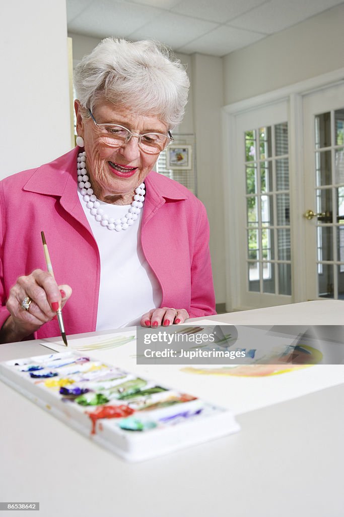 Elderly woman painting with watercolors