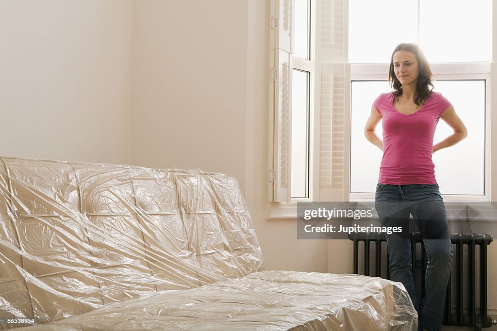 Woman standing by plastic covered sofa