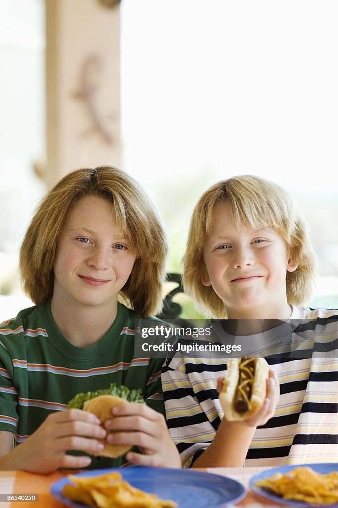 Boys eating hotdog and hamburger