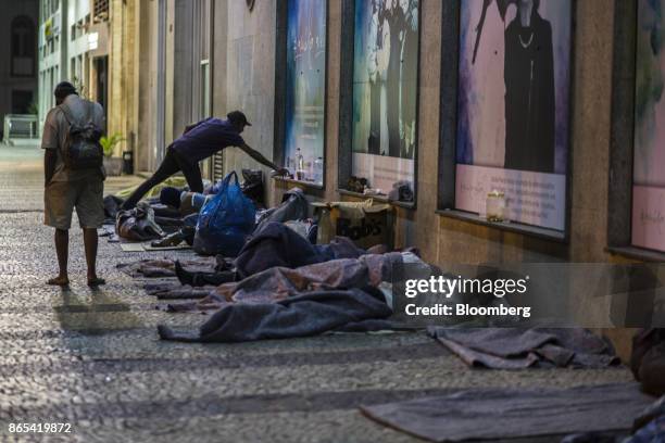 People sleep on a street outside the Public Defender headquarters in Rio de Janeiro, Brazil, on Thursday, Aug. 24, 2017. According to the World Bank,...