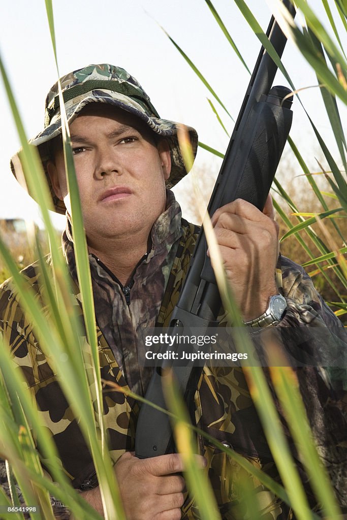 Hunter in reeds with rifle