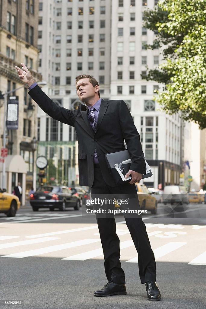 Businessman hailing taxi in city