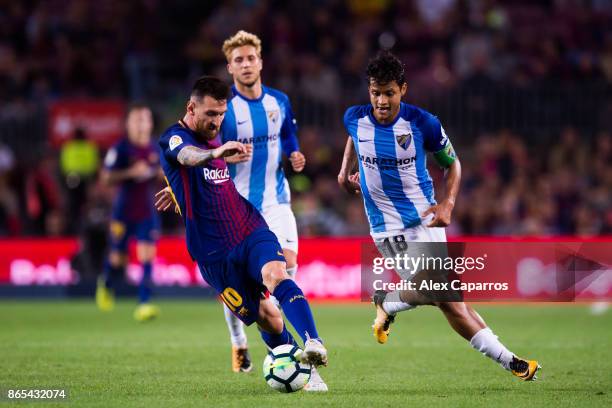 Lionel Messi of FC Barcelona conducts the ball under pressure from Roberto Rosales of Malaga CF during the La Liga match between Barcelona and Malaga...