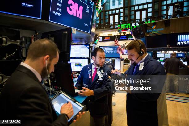 Traders work under monitors displaying 3M Co. Signage on the floor of the New York Stock Exchange in New York, U.S., on Monday, Oct. 23, 2017. U.S....