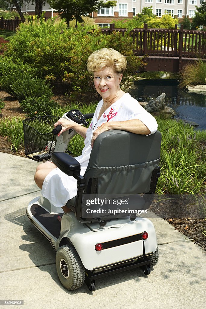 Woman riding motor scooter on sidewalk
