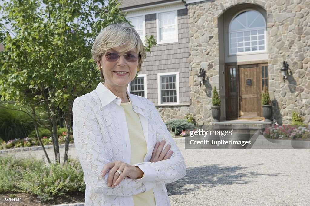 Woman with arms crossed at house exterior