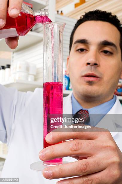 pharmacist pouring liquid into graduated cylinder - measuring cylinder stock pictures, royalty-free photos & images