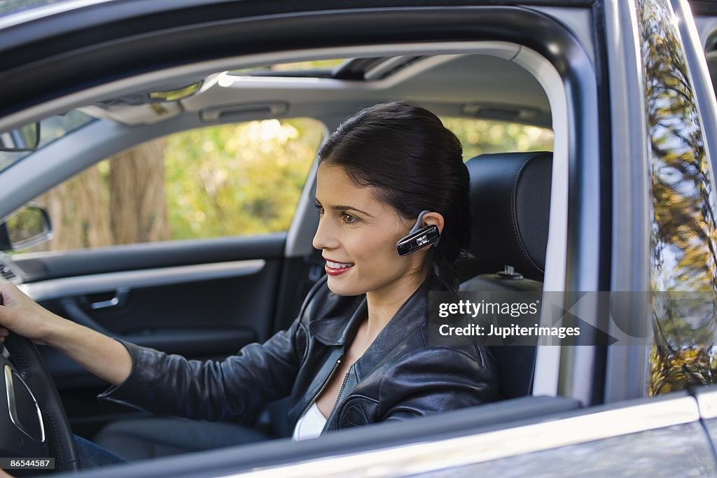 Woman in car with cell phone earphone