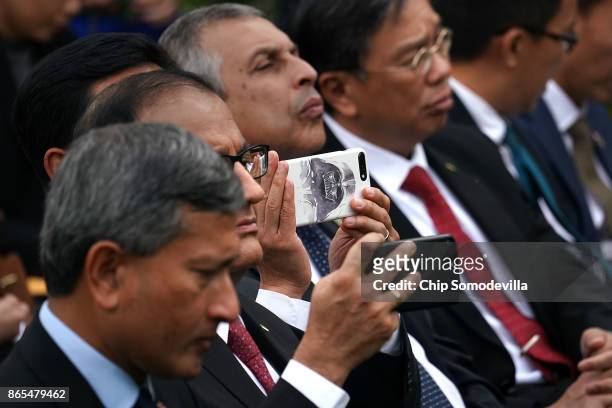 Members of the delegation from Singapore take photographs of U.S. President Donald Trump and Singapore Prime Minister Lee Hsien Loong as they deliver...