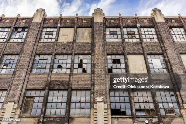 facade of an old brick industry building with broken windows. - abandoned factory stock-fotos und bilder