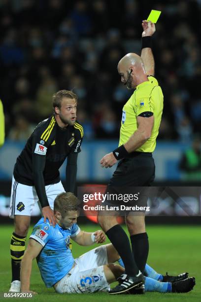 Daniel Sundgren get a yellow card from referee Stefan Johanessen and Anton Tinnerholm of Malmo FF during the allsvenskan match between Malmo FF and...