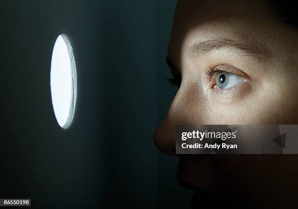 woman looking through illuminated peep hole. - peeking stock-fotos und bilder