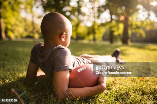 little kid resting with football ball - flag football stock pictures, royalty-free photos & images