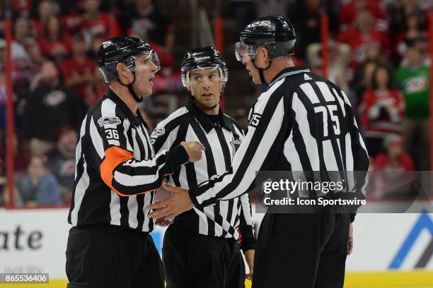 Referees Ghislain Hebert and Dean Morton discuss a play with linesman Derek Amell during a game between the Minnesota Wild and the Carolina...